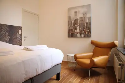 a bedroom with a bed and a chair at Hoogpoort Residence George in Ghent