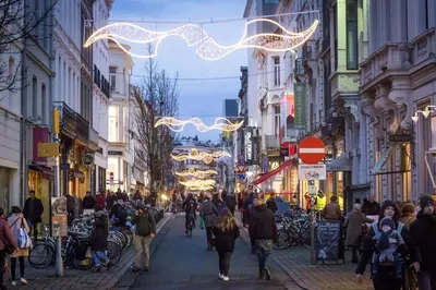a crowd of people walking down a street with christmas lights at Hoogpoort Residence George in Ghent