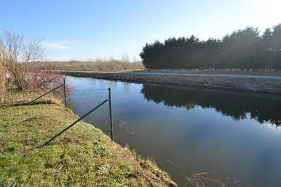 a body of water with a fence next to it at Ars Vivendi in Moerbeke
