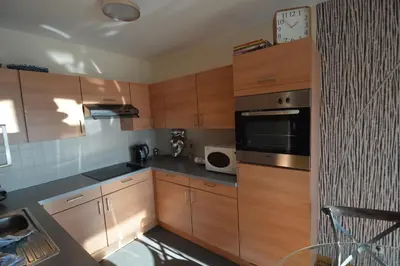 a kitchen with wooden cabinets and a clock on the wall at Ars Vivendi in Moerbeke