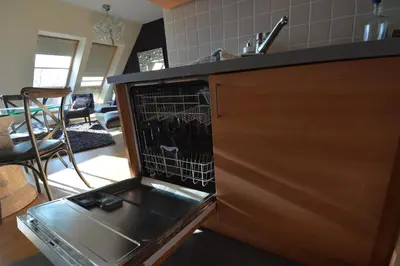 a kitchen with an open dishwasher with a dish rack at Ars Vivendi in Moerbeke