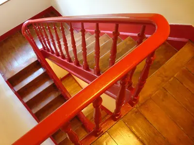 a red railing on a staircase with wooden floors at Brigitte & Alain in Brussels