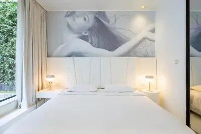 a bedroom with a white bed with a large painting on the wall at B-aparthotel Regent in Brussels
