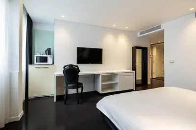 a bedroom with a bed and a desk with a microwave at B-aparthotel Regent in Brussels