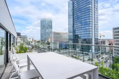 a white table and chairs on a balcony with a view of a city at B-aparthotel Regent in Brussels