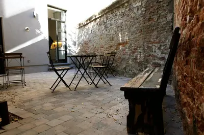 a bench sitting next to a brick wall with a table and chairs at Coeur Sablon in Brussels