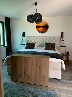 a bedroom with a large bed with a wooden bed frame at Vakantiewoning 't Rysselhof in Kaprijke