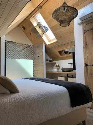 a bedroom with a large bed with wooden ceilings at Vakantiewoning 't Rysselhof in Kaprijke