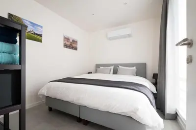 a white bedroom with a large bed with white sheets at Studio Brussels Airport - Central in Zaventem