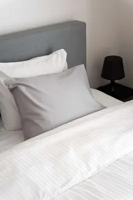 a bed with white sheets and pillows and a lamp at Studio Brussels Airport - Central in Zaventem