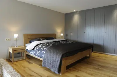 a bedroom with a large bed and a wooden floor at Logies De Hessie in Turnhout