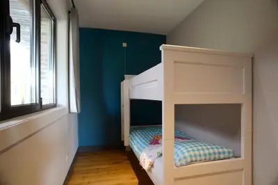 a white bunk bed in a room with blue walls at Logies De Hessie in Turnhout