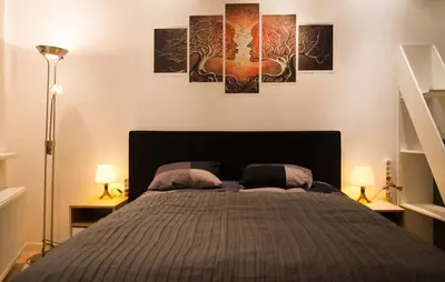 a bedroom with a bed with three paintings on the wall at full 4 floors house at the center in Antwerp