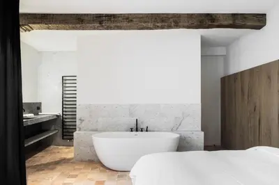 a white bathroom with a tub and a bed at Hotel Riga in Antwerp