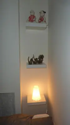 a light on a wall with shelves and a bed at Antwerp old town triplex apartment in Antwerp