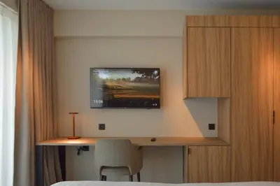 a bedroom with a desk with a tv on the wall at Hotel De Zalm in Herentals