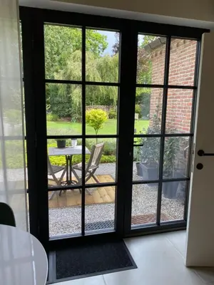 a sliding glass door with a view of a patio at de graslelie in Schoten