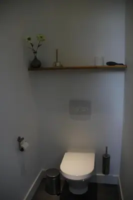 a white bathroom with a toilet and a shelf at B&B Le Verger in Brussels