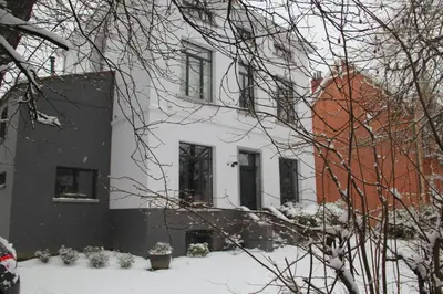 a white building with snow on the ground at B&B Le Verger in Brussels