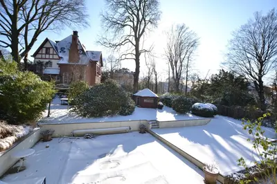 a yard covered in snow with a house in the background at Maison Montana in Brussels