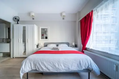 a bedroom with a large bed with a red curtain at Luxury Studio In the EU Area in Brussels