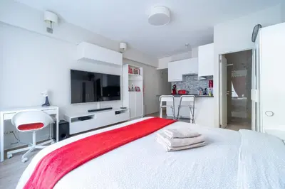 a white bedroom with a large bed with a red blanket at Luxury Studio In the EU Area in Brussels