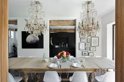 a dining room with a wooden table and chandeliers at B&B Park7 in Huldenberg