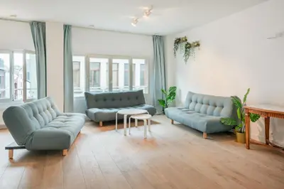a living room with couches and a table and windows at Light House Lodge. Apartment in Center of Antwerp in Antwerp