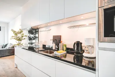 a kitchen with white cabinets and a black counter top at Light House Lodge. Apartment in Center of Antwerp in Antwerp