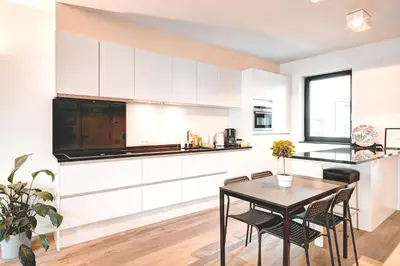a kitchen with white cabinets and a table and chairs at Light House Lodge. Apartment in Center of Antwerp in Antwerp