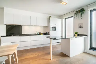 a kitchen with white cabinets and a table at Light House Lodge. Apartment in Center of Antwerp in Antwerp