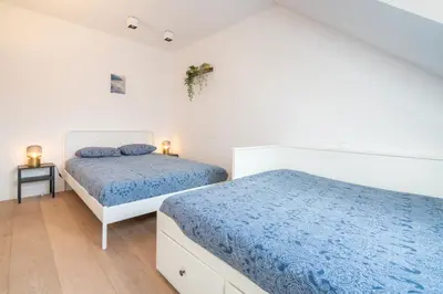 two beds in a white room with blue sheets at Light House Lodge. Apartment in Center of Antwerp in Antwerp
