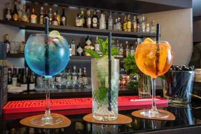 three cocktails sitting on a counter in a bar at Martin's Patershof in Mechelen