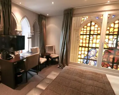 a bedroom with a bed and a desk and a window at Martin's Patershof in Mechelen