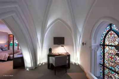 a bedroom with a bed and a desk and a stained glass window at Martin's Patershof in Mechelen