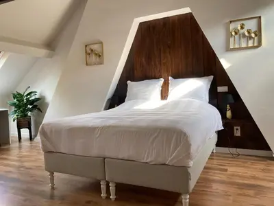 a bedroom with a large bed with a wooden headboard at RS10 B&B Turnhout in Turnhout