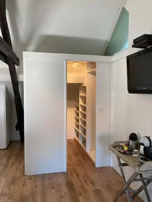 a room with a white wall and a tv and a table at RS10 B&B Turnhout in Turnhout