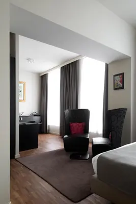 a bedroom with a bed and a chair and a desk at Hotel Karmel in Herentals