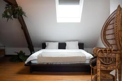 a bedroom with a bed and a chair and a window at PAKHUIS in Ghent