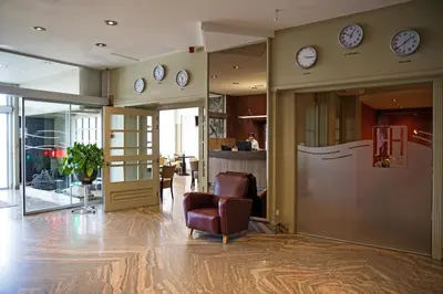 a lobby with a chair and clocks on the wall at Antwerp Harbour Hotel in Antwerp