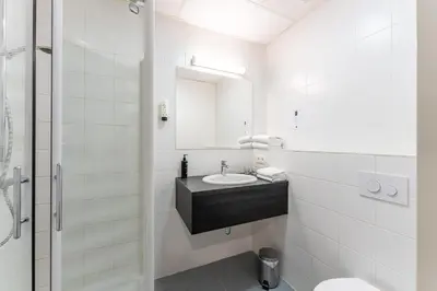 a white bathroom with a sink and a mirror at Antwerp Harbour Hotel in Antwerp