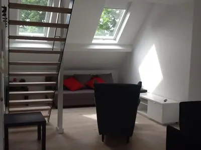 a room with a staircase and a bed and a chair at Akker duplex in Mortsel