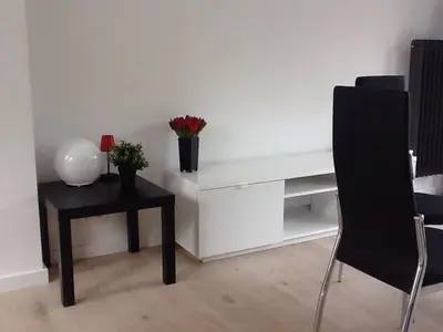 a table with a vase of flowers and a table with a chair at Akker duplex in Mortsel