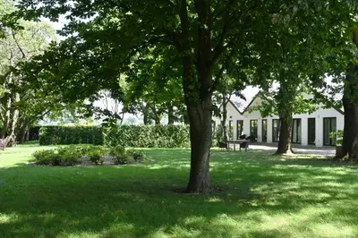 a white house with trees in a yard at Landlord bij Leuven in Holsbeek