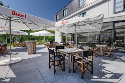 an outdoor patio with tables and chairs and umbrellas at Hotel Ter Elst in Edegem
