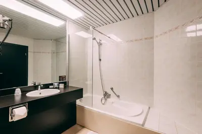 a bathroom with a tub and a sink and a shower at Hotel Ter Elst in Edegem