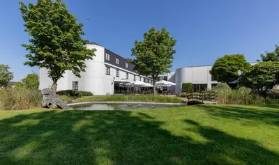 a building with a pond in the middle of a yard at Hotel Ter Elst in Edegem