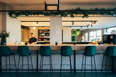 a bar at a restaurant with green chairs at Hotel Ter Elst in Edegem