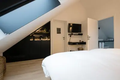 a bedroom with a white bed and a black door at B&B Amelhof in Meise