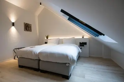 a bedroom with a large bed in a attic at B&B Amelhof in Meise